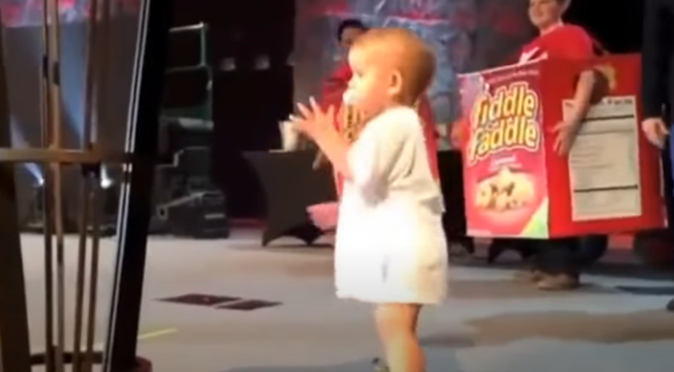Cute toddler climbs onto stage with his singing dad –  10 seconds later the crowd goes wild